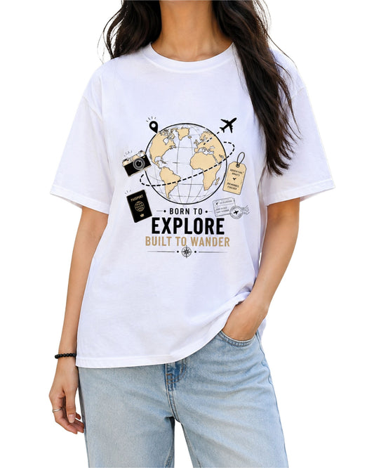 White graphic T-shirt design with a vintage travel globe, airplane, camera, passport and travel tag, featuring the text “Born to Explore – Built to Wander” 