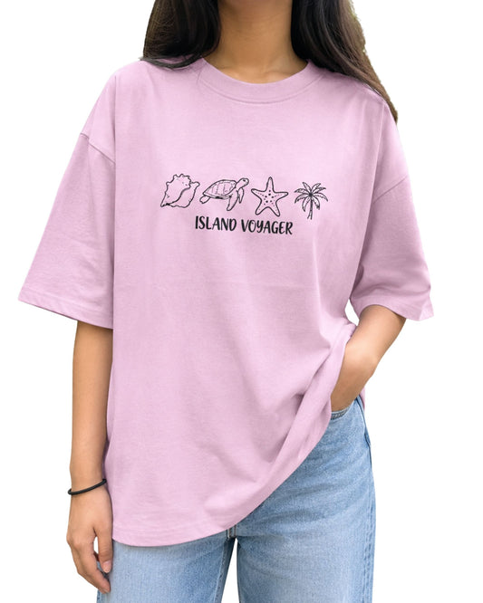 Oversized graphic T-shirt featuring hand-drawn coastal icons with a seashell, sea turtle, starfish, palm tree, and “Island Voyager” text light baby pink