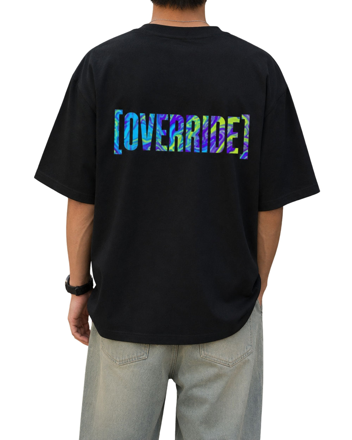 Black oversized T-shirt with a large multicolor glitch-style “OVERRIDE” graphic printed across the upper back.