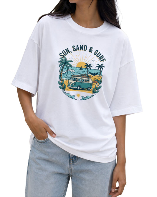 White oversized graphic T-shirt featuring a retro “Sun, Sand & Surf” beach design with a vintage van, palm trees, ocean waves, and sunset artwork.