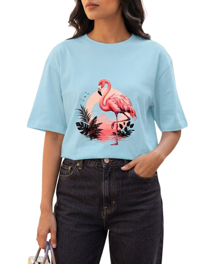 A model wearing a light blue oversized t-shirt featuring a flamingo and tropical sunset graphic design Baby Blue