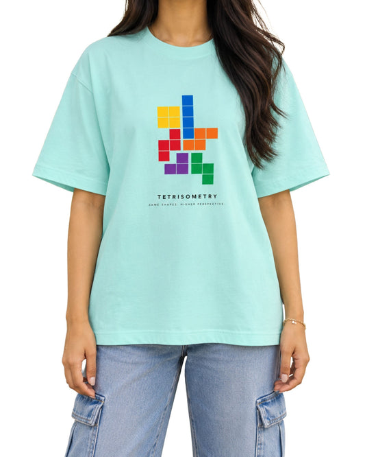 Young Indian woman wearing a mint T-shirt with a colorful Tetris-inspired geometric graphic and “TETRISOMETRY” text.