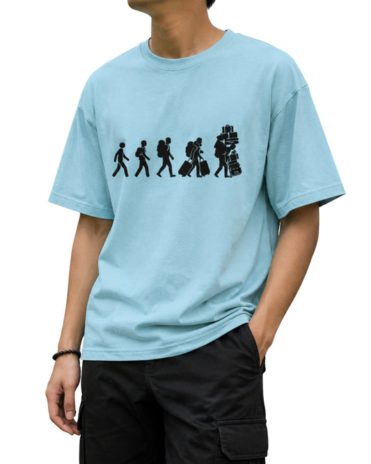 Oversized T-shirt with a travel evolution graphic showing a traveller progressing from walking with a backpack to carrying multiple suitcases and stacked luggage baby blue.