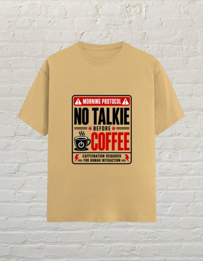 CoreTeez unisex beige cotton t-shirt featuring a No Talkie Before Coffee graphic print on a white brick background.
