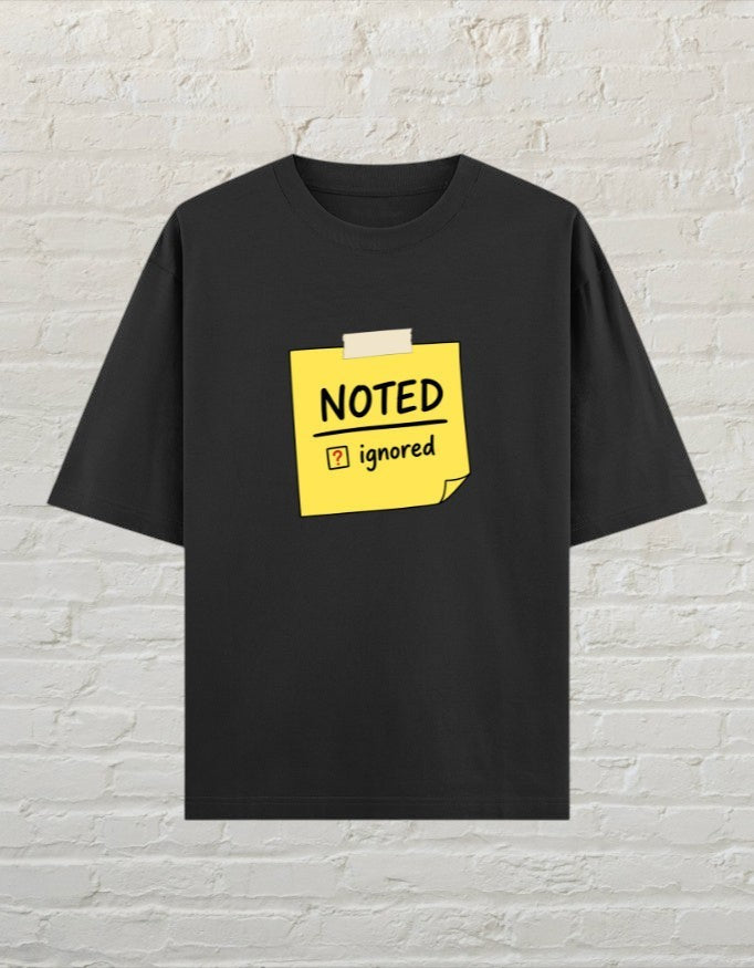CoreTeez black oversized cotton unisex t-shirt featuring a yellow sticky note graphic with Noted and Ignored text.