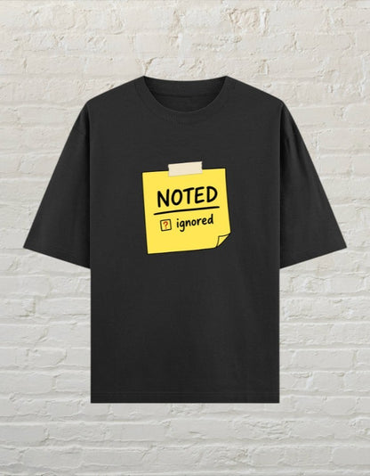 CoreTeez black oversized cotton unisex t-shirt featuring a yellow sticky note graphic with Noted and Ignored text.