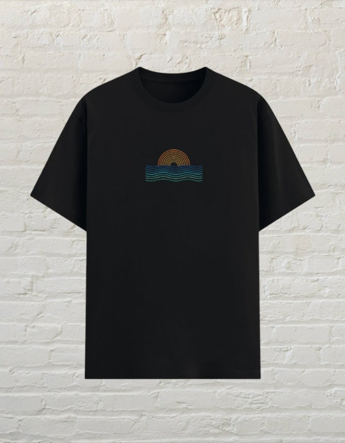 CoreTeez unisex black poly-cotton graphic t-shirt featuring a minimalist sunset and ocean wave design on the chest.