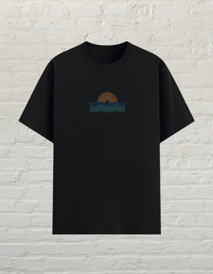 CoreTeez unisex black poly-cotton graphic t-shirt featuring a minimalist sunset and ocean wave design on the chest.