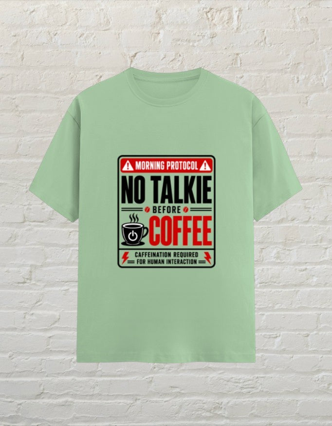 CoreTeez unisex jade cotton t-shirt featuring a No Talkie Before Coffee graphic print on a brick background.