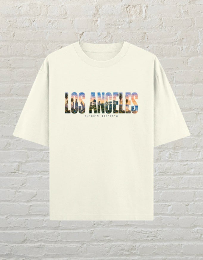 CoreTeez oversized off white cotton unisex t-shirt featuring a Los Angeles graphic print with palm trees and city skyline.