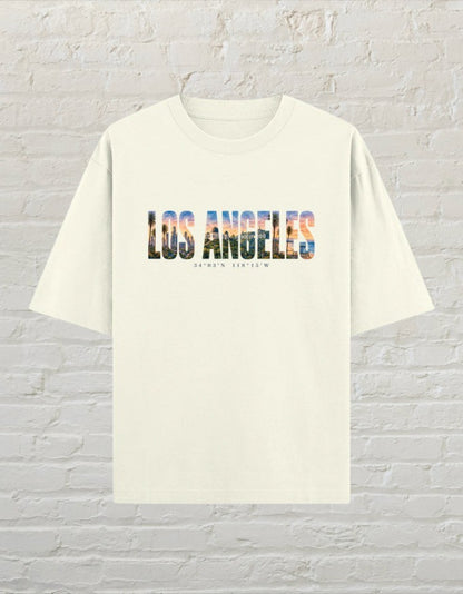 CoreTeez oversized off white cotton unisex t-shirt featuring a Los Angeles graphic print with palm trees and city skyline.