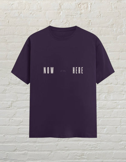CoreTeez unisex  purple 100% cotton t-shirt featuring a minimalist white NOW HERE graphic print